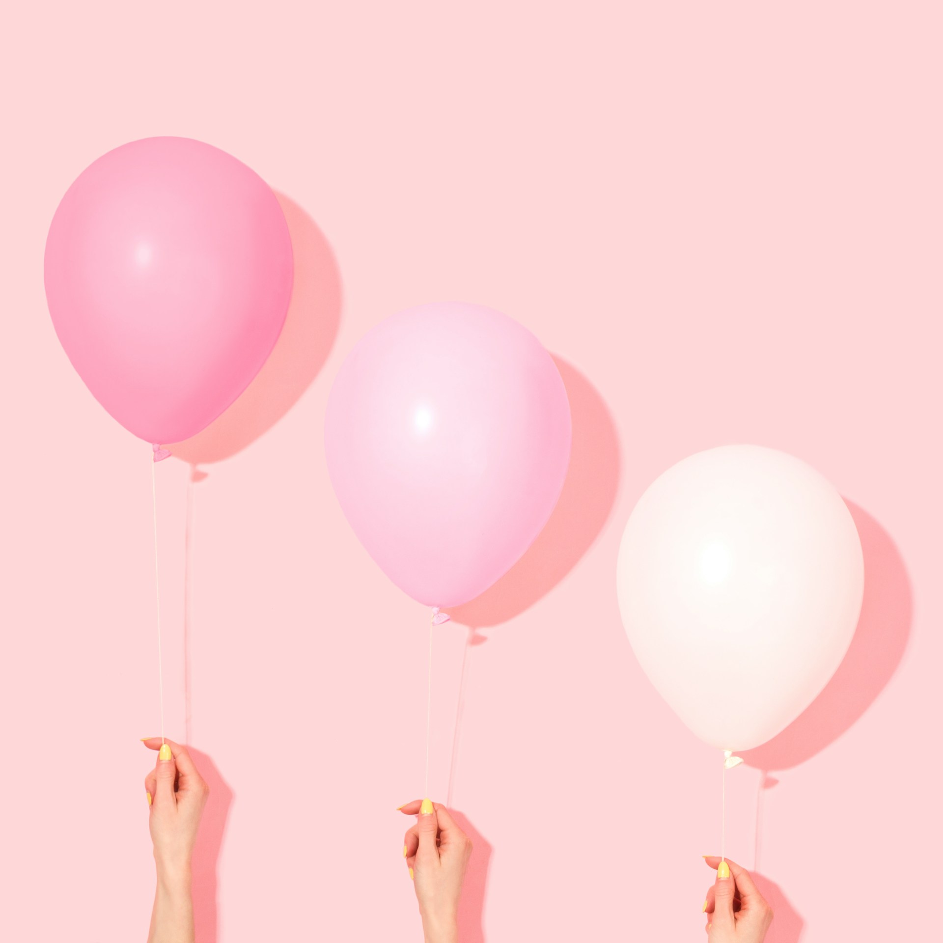 Person holding pink and white balloons