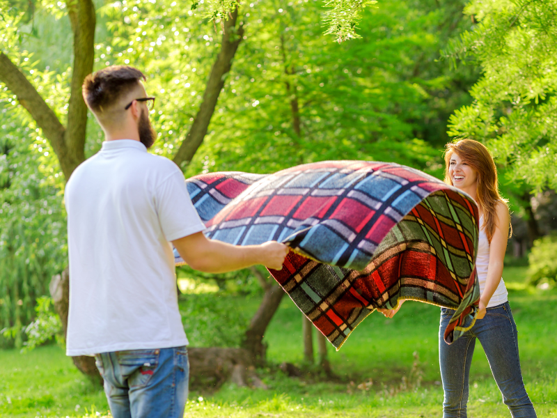 Custom fall promotional picnic blankets spread on autumn grass during an outdoor concert.